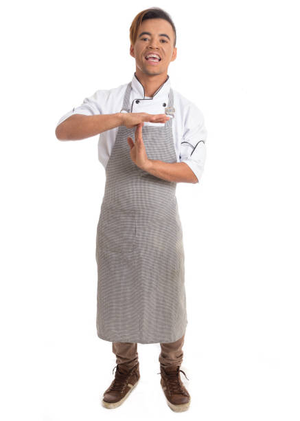 istock Young man gesturing with his hands. He asks for time. Black cook wears apron. Isolated on white background. 903036830