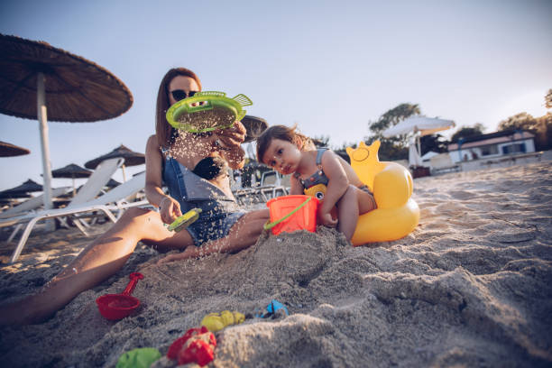istock Mother and cute daughter sieving sand at the beach 903036994