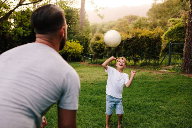 père et fils, jouant avec un ballon de football - throwing football men ball photos et images de collection