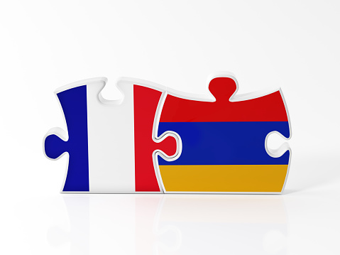 Jigsaw puzzle pieces textured with Armenian and French flags on white. Horizontal composition with copy space. Clipping path is included.