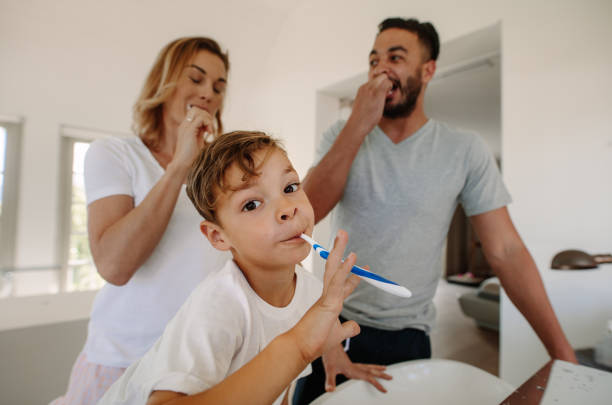 istock Little boy brushing teeth with his parents 903046940