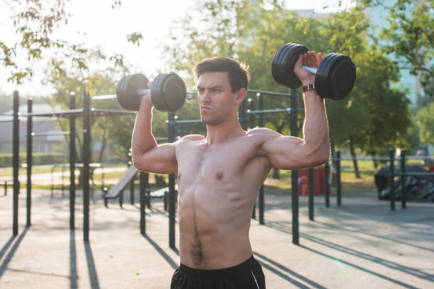 istock Muscular male athlete with arms raised doing lifting exercises dumbbells. 903050072
