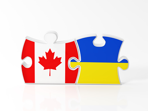 Jigsaw puzzle pieces textured with Canadian and Ukrainian flags on white. Horizontal composition with copy space. Clipping path is included.