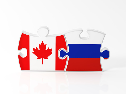 Jigsaw puzzle pieces textured with Canadian and Russian flags on white. Horizontal composition with copy space. Clipping path is included.