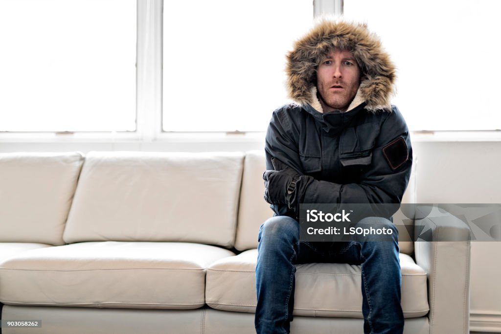 Man With Warm Clothing Feeling The Cold Inside House on the sofa A Man With Warm Clothing Feeling The Cold Inside House Cold And Flu Stock Photo
