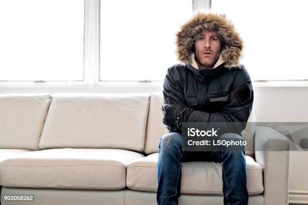 Man With Warm Clothing Feeling The Cold Inside House On The Sofa Stock Photo - Download Image Now
