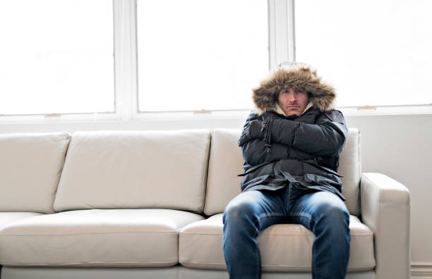 homme avec vêtements sentiment le froid à l’intérieur de maison chaude sur le canapé - room temperature photos et images de collection