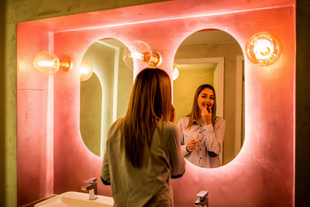 Woman paints lips in the toilet The woman paints lips in the toilet. Attractive happy woman paints lips with lipstick in the bathroom of a restaurant restaurant mirror stock pictures, royalty-free photos & images