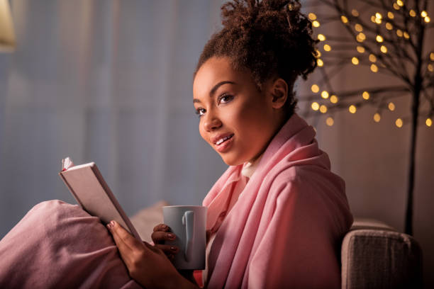 istock Carefree young woman reading on sofa 903065304