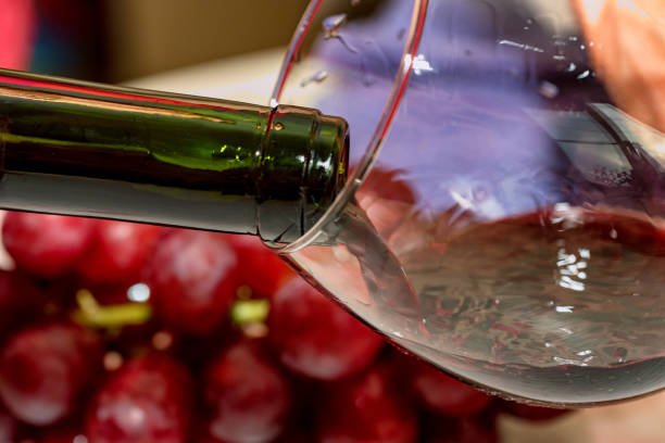 istock Pouring red wine into the glass against grape 903073036