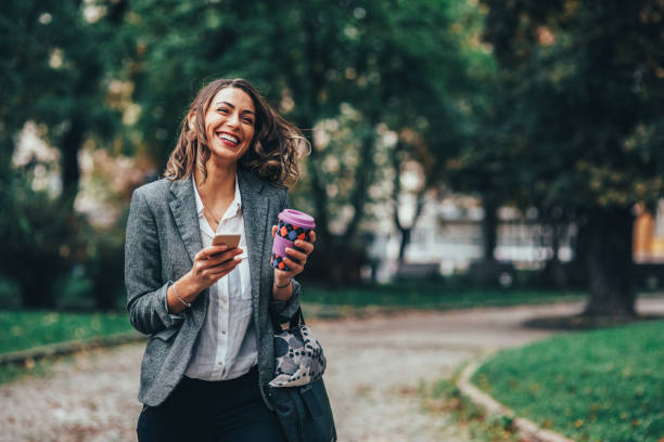Woman texting and drinking coffee in the park