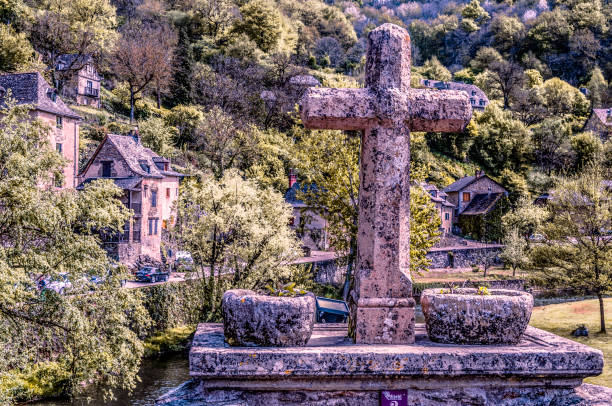Catholic cross on bridge that crosses the river Aveyron in the medieval village of Belcastel France