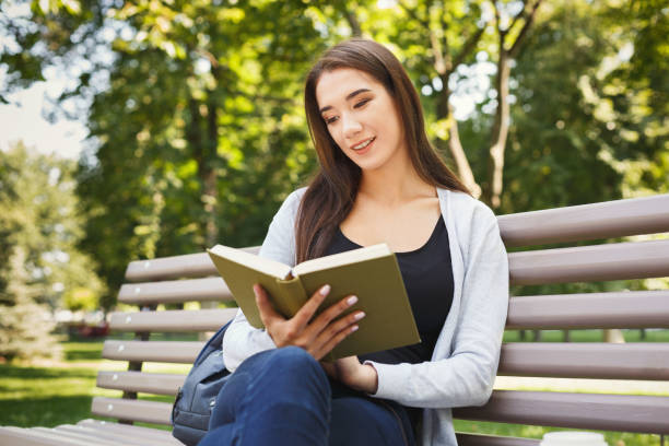 istock Young woman reading book in park copy space 903089558