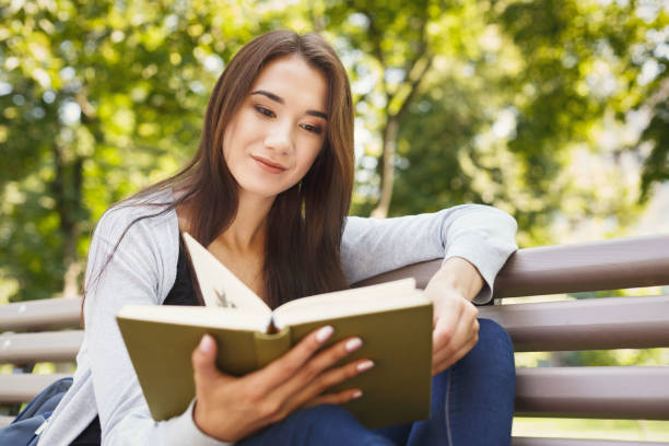 istock Young woman reading book in park copy space 903089594