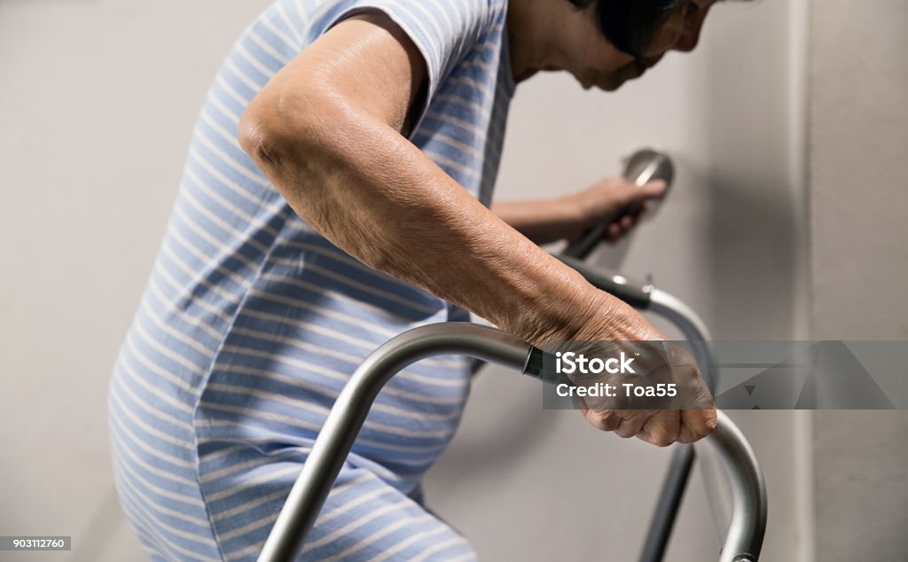 Elderly woman holding on handrail and walker for safety walk steps Senior Adult Stock Photo