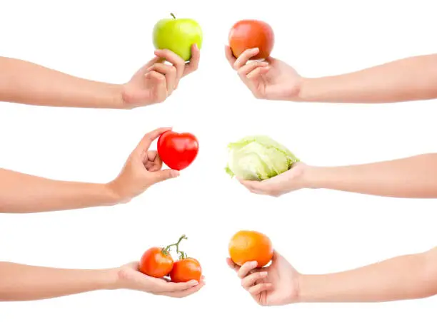 Photo of Isolated chef's hands holding fruits and vegetables, heart, red and green apple, orange, tomato on white background