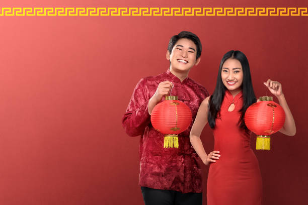 istock Beautiful chinese couple holding red lanterns on red background 903146176