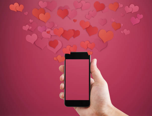 istock Hand holding Mobile smart phone, with floating hearts. Valentines, love message and texting concept 903149494