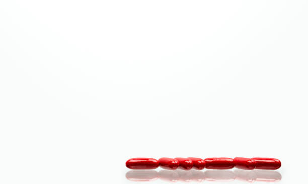 istock Red capsule pills isolated on white background with shadows and copy space for text. Vitamin and supplement for pregnancy and elderly people. 903150938