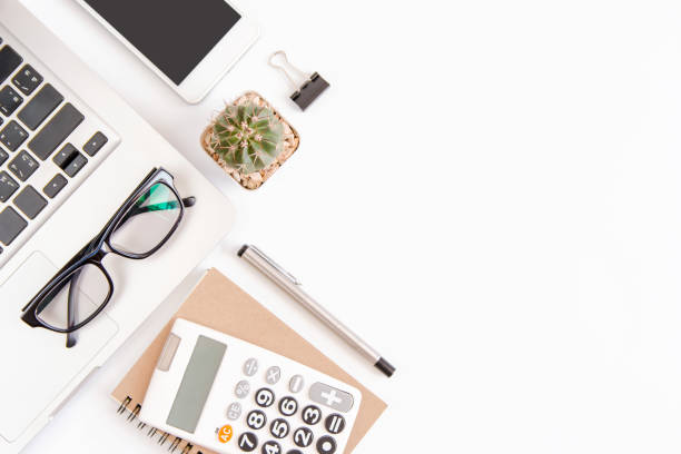 istock White office desk table, workspace office with laptop, smartphone black screen,pen,calculator, glasses, Top view with copy space 903156740
