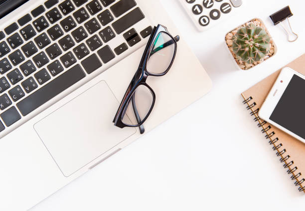 istock White office desk table, workspace office with laptop, smartphone black screen,pen,calculator, glasses, Top view with copy space 903157060