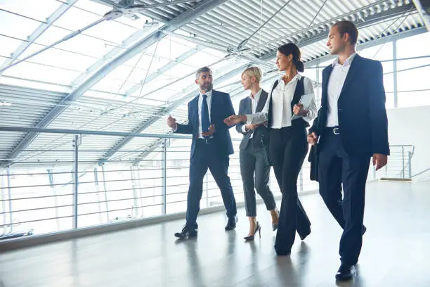 Group of business colleagues walking over lobby and discussing company situation