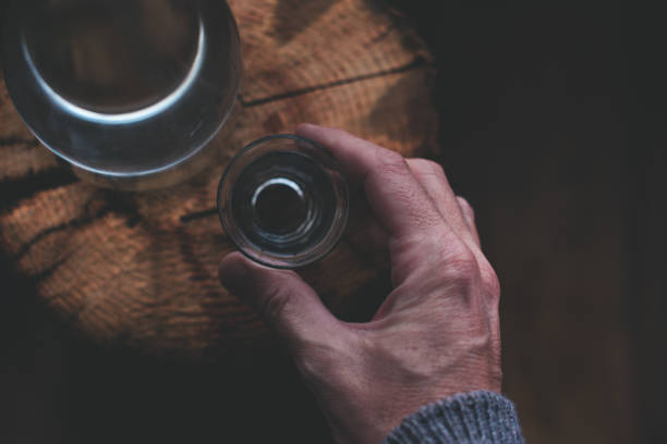 Man drinking strong alcohol drink from a shot glass Man drinking strong alcohol drink from a shot glass, close up of hand, overhead view with selective focus serbian raki stock pictures, royalty-free photos & images