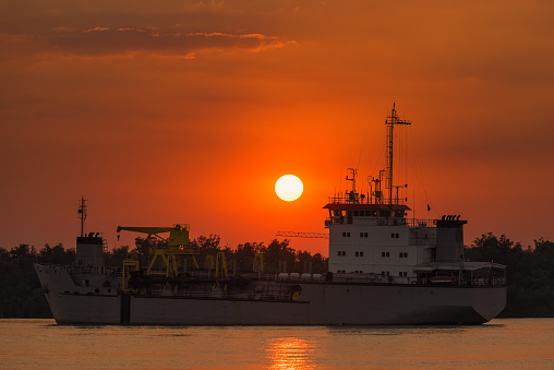Cargo ship in the Chao Phraya River at estuary in sunsrt time at Samut Prakan, Thailand.
