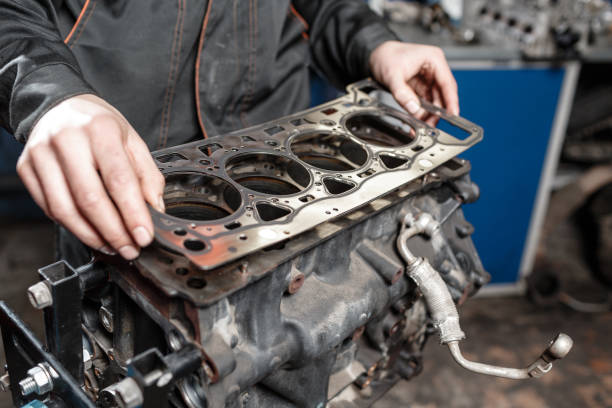 sealing gasket in hand. the mechanic disassemble block engine vehicle. engine on a repair stand with piston and connecting rod of automotive technology. interior of a car repair shop. - auto repair shop mechanic piston industrial equipment imagens e fotografias de stock