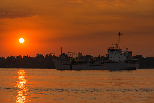 Cargo ship in the Chao Phraya River at estuary in sunsrt time at Samut Prakan, Thailand.