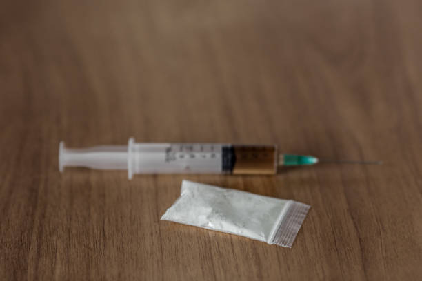 istock plastic packet with cocaine powder and syringe on wooden table 903188146