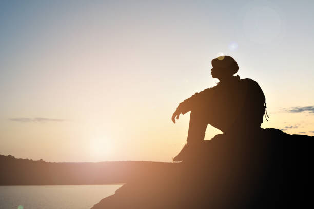 istock Silhouette Man Sitting Against Sky During Sunset 903190268