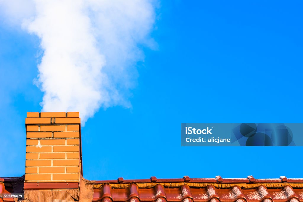 Modern house roof with chimney smoke, air pollution and smog in winter, ecological issues Chimney Stock Photo