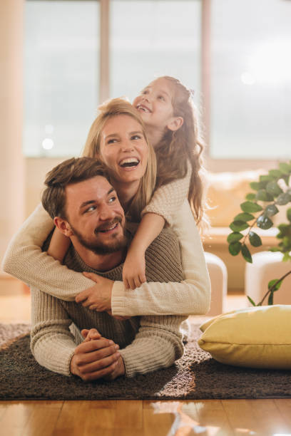 istock Happy family having fun while making human pyramid on carpet at home. 903190934
