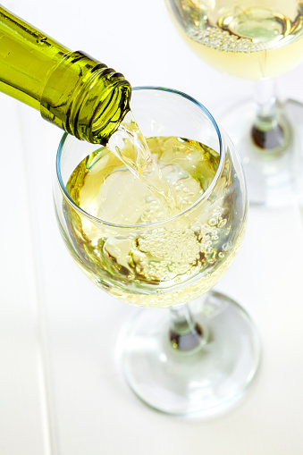 Glass of White Wine Being Poured - white wine being poured into a glass, looking down. Semi sparkling moscato, Australian wine.