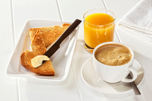 Coffee Toast Orange Juice - a light breakfast of espresso coffee, orange juice and toast with soft polyunsaturated margarine. Front to back focus.