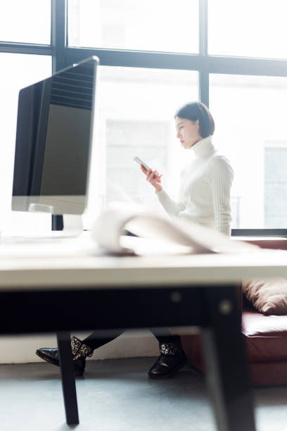istock portrait of young woman using phone by window 903205554