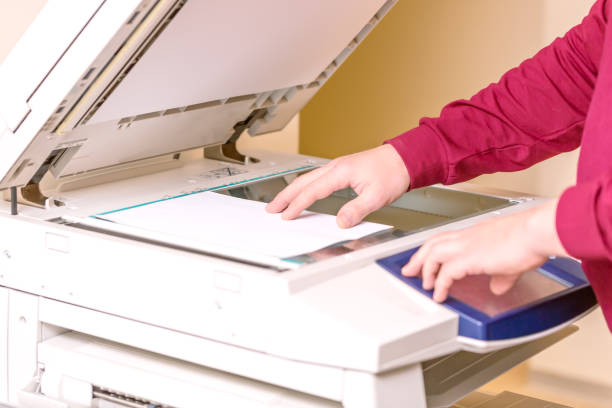 istock Man putting paper sheet on printer for scanning. Office work concept. 903206564