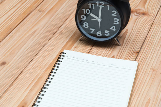 istock Alarm clock and notebook with pen on wooden floor, empty space for text. 903212558