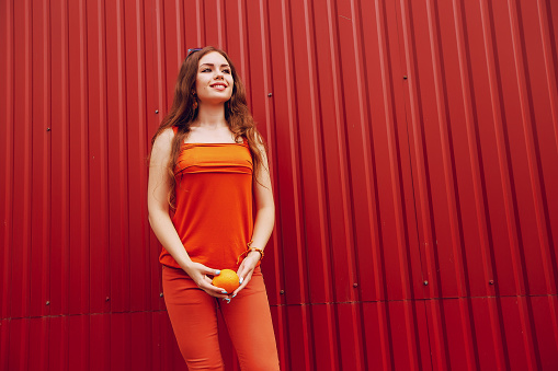 beautiful girl dressed in orange outfit holding a healthy orange to encourage a healthy lifestyle