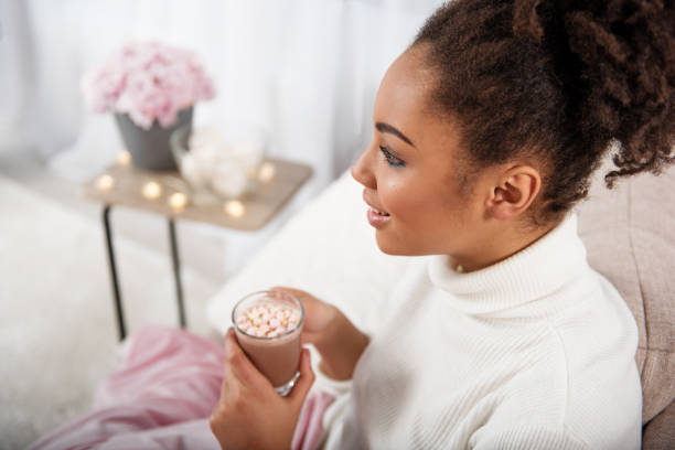 istock Relaxed african girl tasting cocoa with marshmallows 903218306