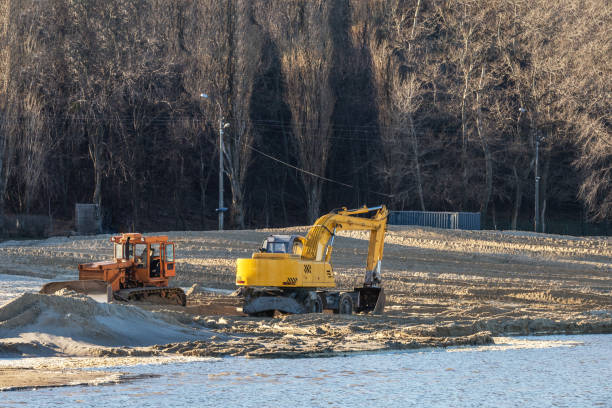 istock Excavator or digger and excavators working on ground. Industrial machinery at working construction building site near river. Sunny autumn day with a clear blue sky. 903221954