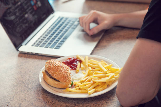 laptop with lunch, hamburger and french chips - eating sandwich emotional stress food imagens e fotografias de stock