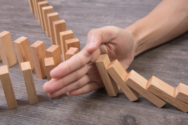istock hand stopping wooden block domino. concept prevent and solution. 903225814