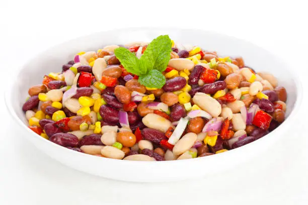 Three bean salad with sweetcorn, roasted red peppers and red onion in a vinaigrette dresing.