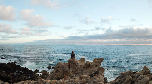 istock Young boy sits on the rocks and admires the view 903232852