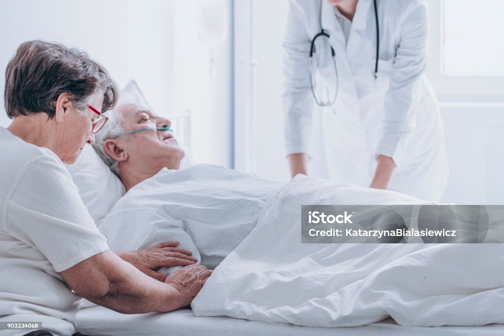 Doctor pronouncing death of patient Doctor pronouncing death of an elderly patient in a presence of his spouse Death Stock Photo