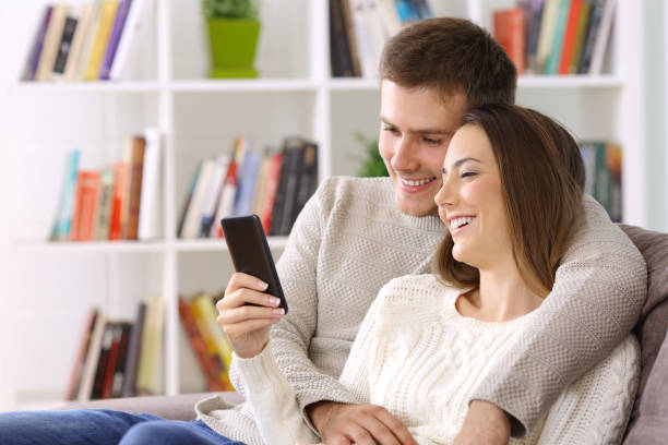 istock Couple watching media on a smart phone sitting at home 903235194