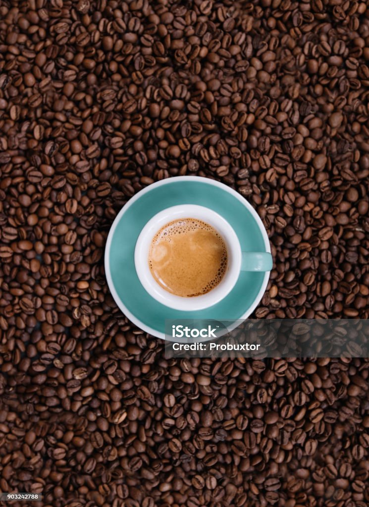 Delicious fresh morning espresso with a beautiful crema in a ceramic green cup with a saucer on the coffee beans background, top view Espresso Stock Photo