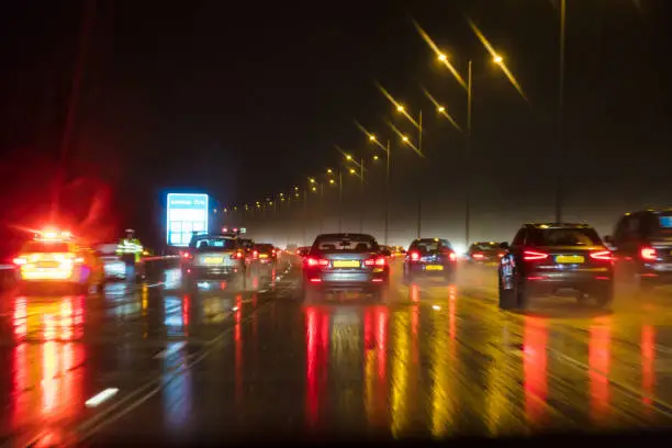 Motion blurred photograph of traffic at in night in the rain on a British motorway with police officer and car